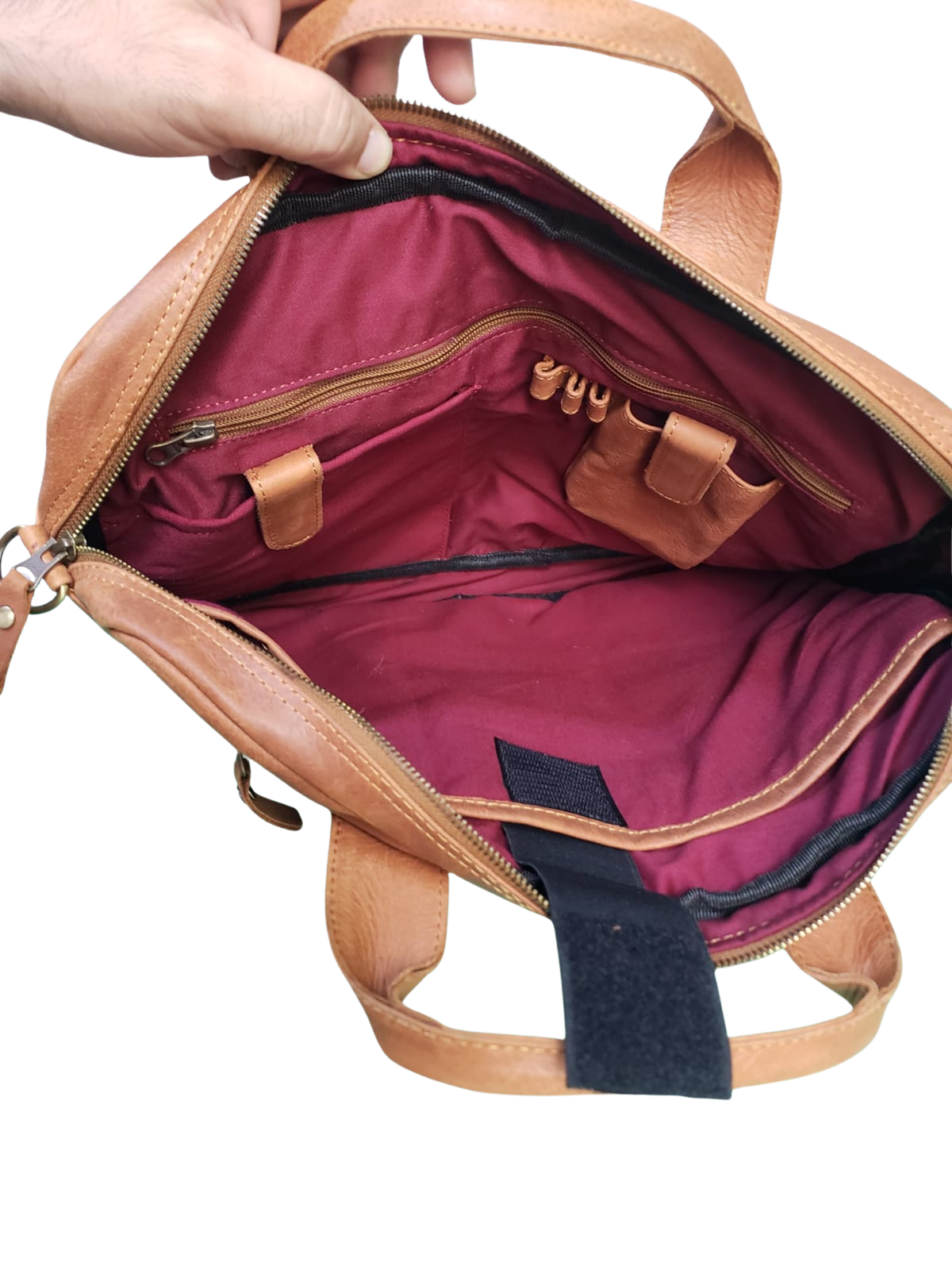 Brown leather bag with open zipper showing red interior on a white background